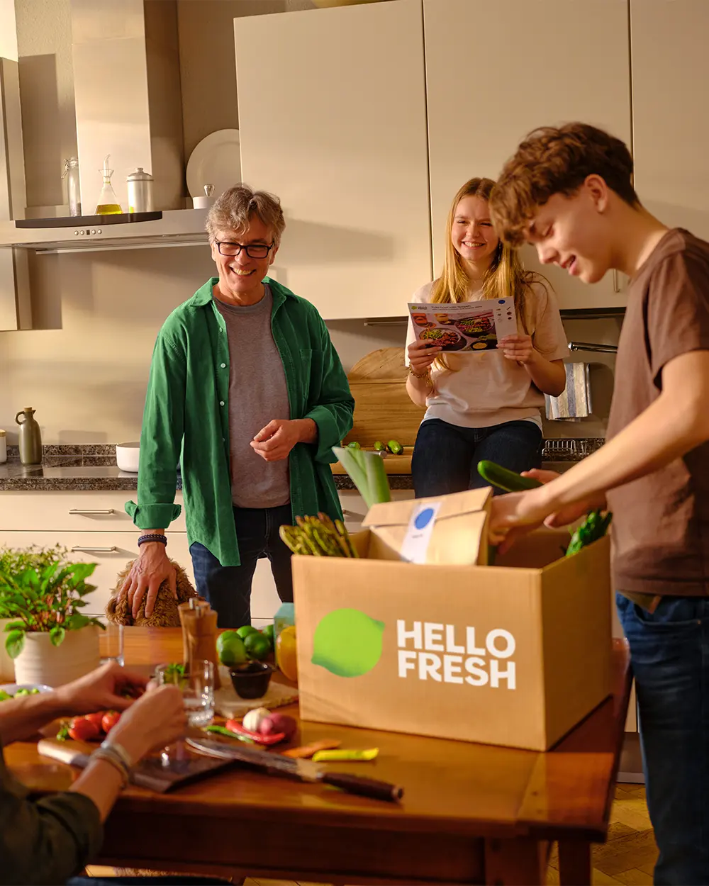 Een gezin pakt samen een maaltijdbox van HelloFresh uit in de keuken