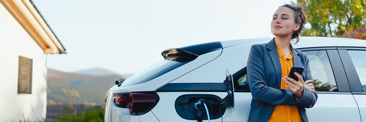 Vrouw kijkt tevreden terwijl zij haar auto oplaadt