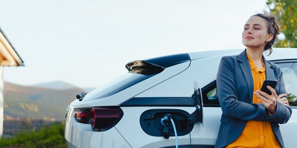 Vrouw kijkt tevreden terwijl zij haar auto oplaadt